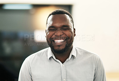 Buy stock photo Shot of a handsome young businessman standing alone in the office and laughing