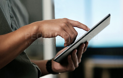Buy stock photo Cropped shot of an unrecognizable businessman standing alone in the office and using a digital tablet
