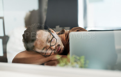 Buy stock photo Shot of a handsome young businessman lying on his desk and sleeping in the office