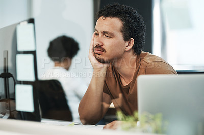 Buy stock photo Shot of a handsome young businessman sitting in the office and feeling bored