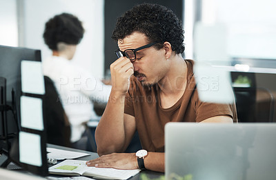 Buy stock photo Shot of a handsome young businessman sitting in the office and feeling stressed