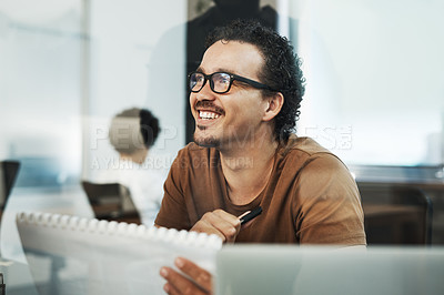 Buy stock photo Shot of a handsome young businessman sitting in the office and looking at paperwork