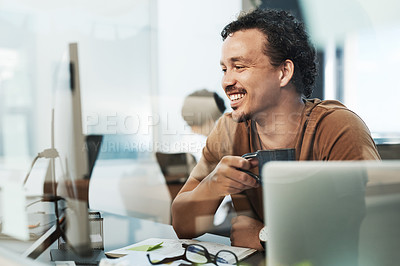 Buy stock photo Shot of a handsome young businessman sitting in the office and drinking coffee while using his computer