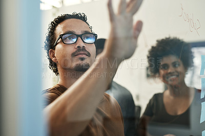 Buy stock photo Shot of a young group of businesspeople standing together in the office and using a visual aid for planning