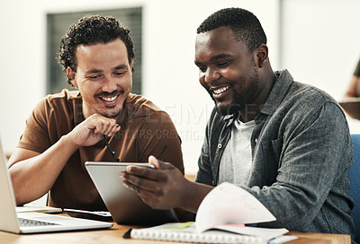 Buy stock photo Shot of two young businessmen sitting together and using a digital tablet in the office