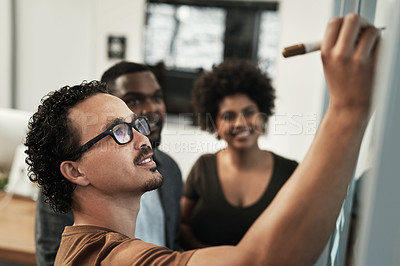 Buy stock photo Shot of a young group of businesspeople standing together in the office and using a visual aid for planning