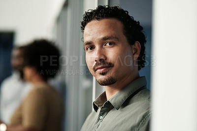 Buy stock photo Shot of a handsome young businessman standing in the office during the day