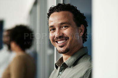 Buy stock photo Shot of a handsome young businessman standing in the office during the day