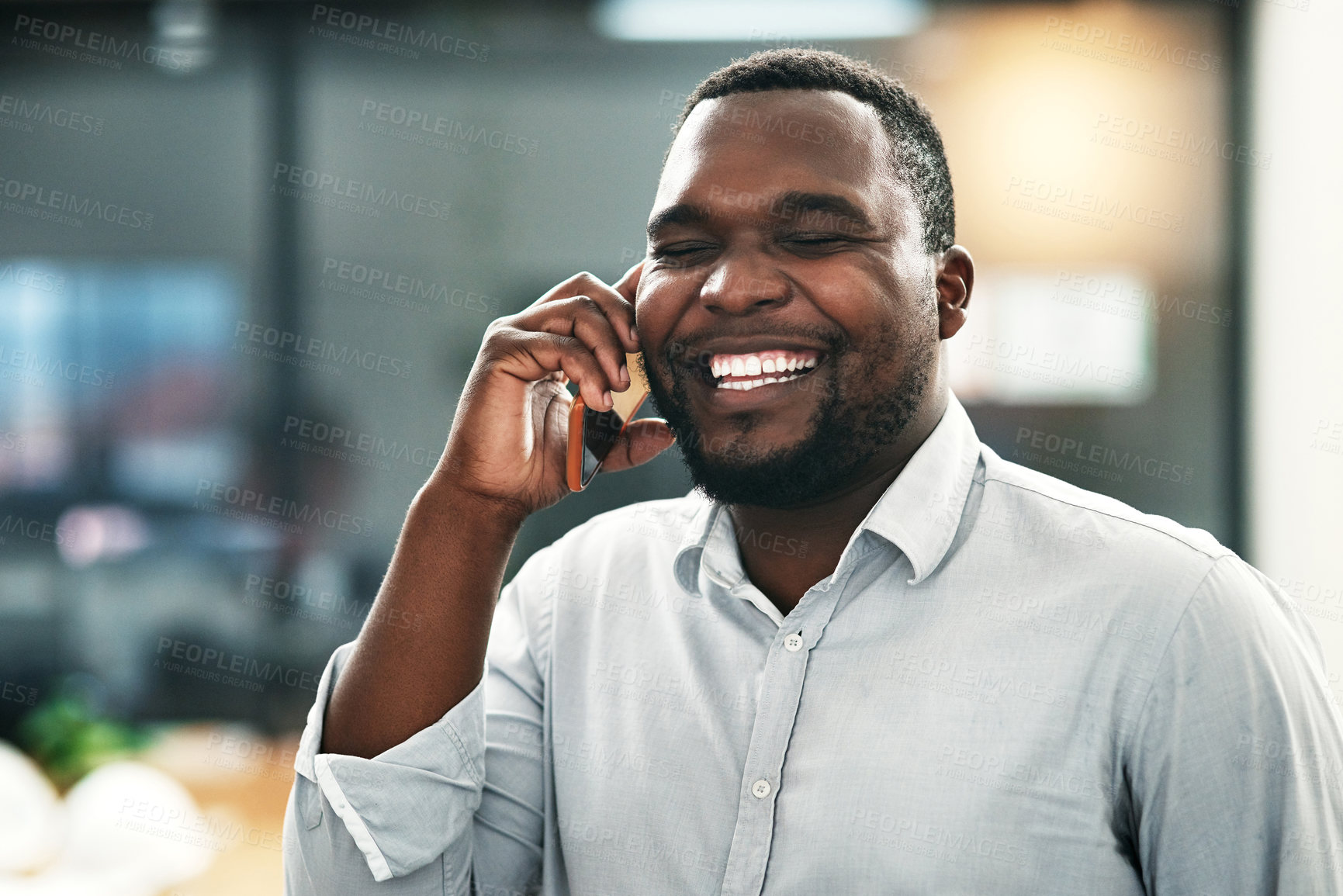 Buy stock photo Shot of a handsome young businessman standing in the office and using his cellphone