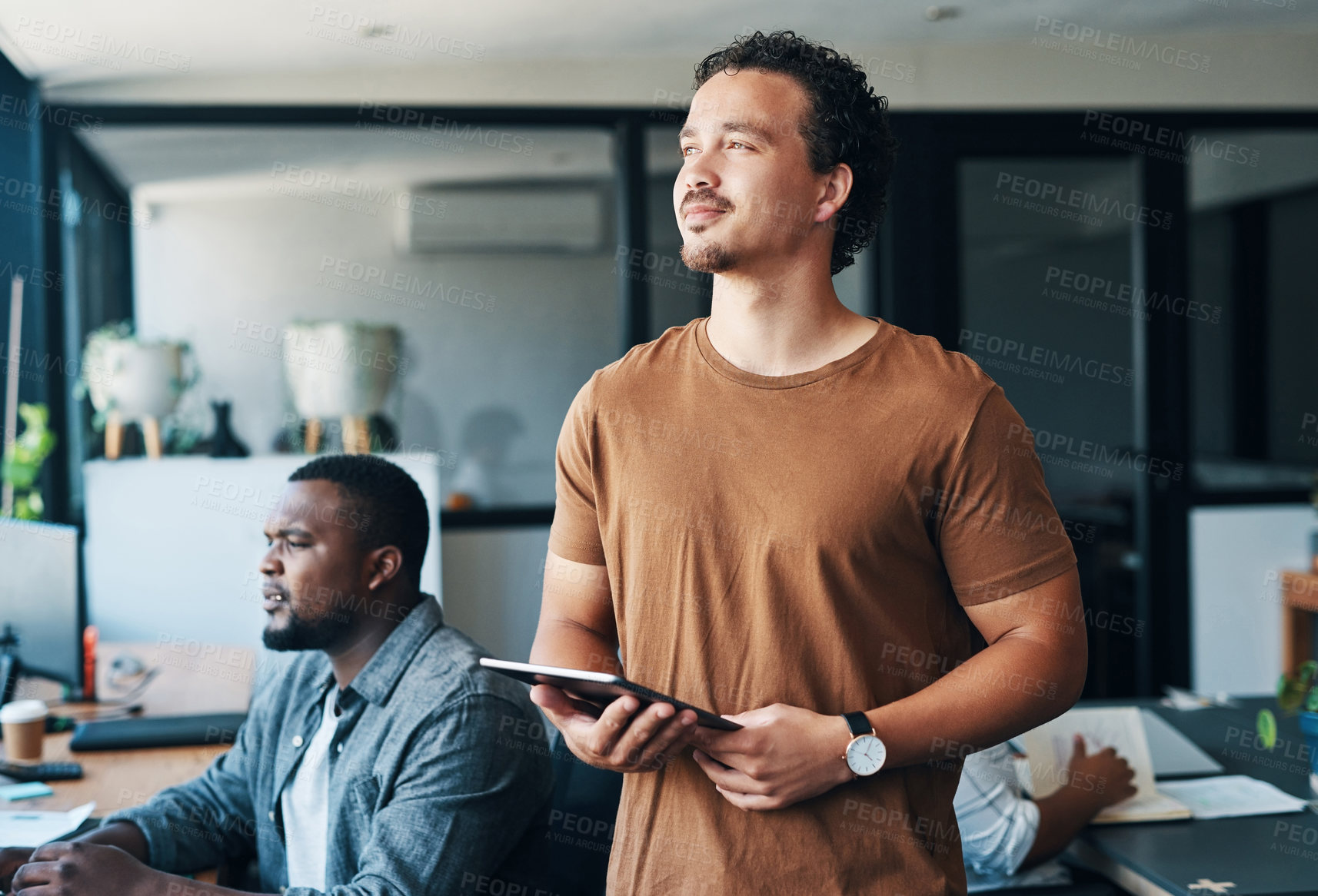 Buy stock photo Shot of a young businessman using a digital tablet in an office