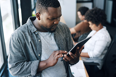 Buy stock photo Shot of a young businessman using a digital tablet in an office