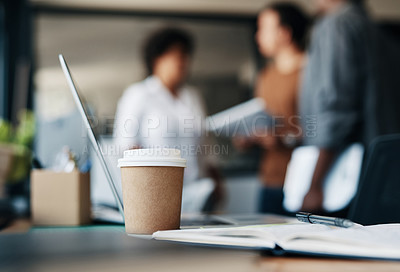 Buy stock photo Shot of a cup of coffee and a notebook with a group of businesspeople in the background