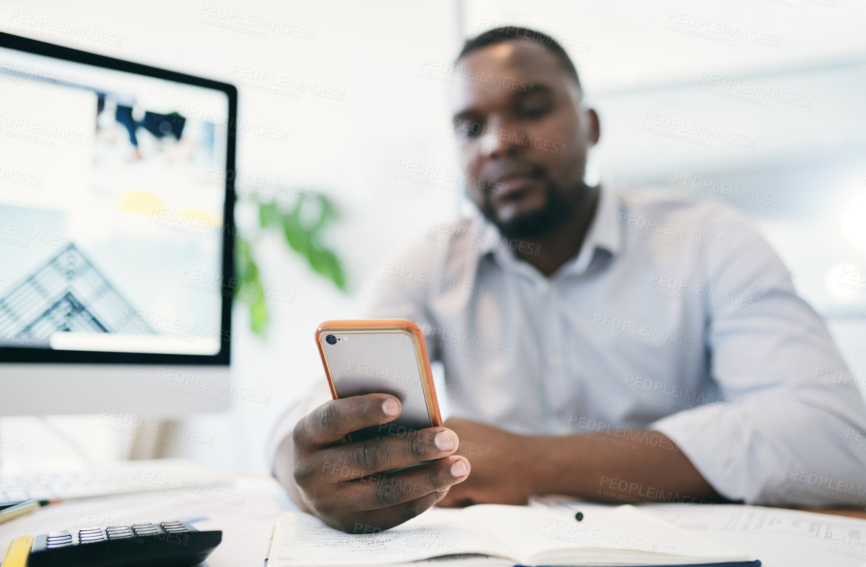 Buy stock photo Shot of a young businessman using a cellphone in an office