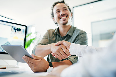Buy stock photo Shot of a young businessman shaking hands with a colleague in an office
