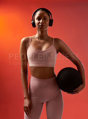 Buy stock photo Studio portrait of a sporty young woman holding an exercise ball against a red background