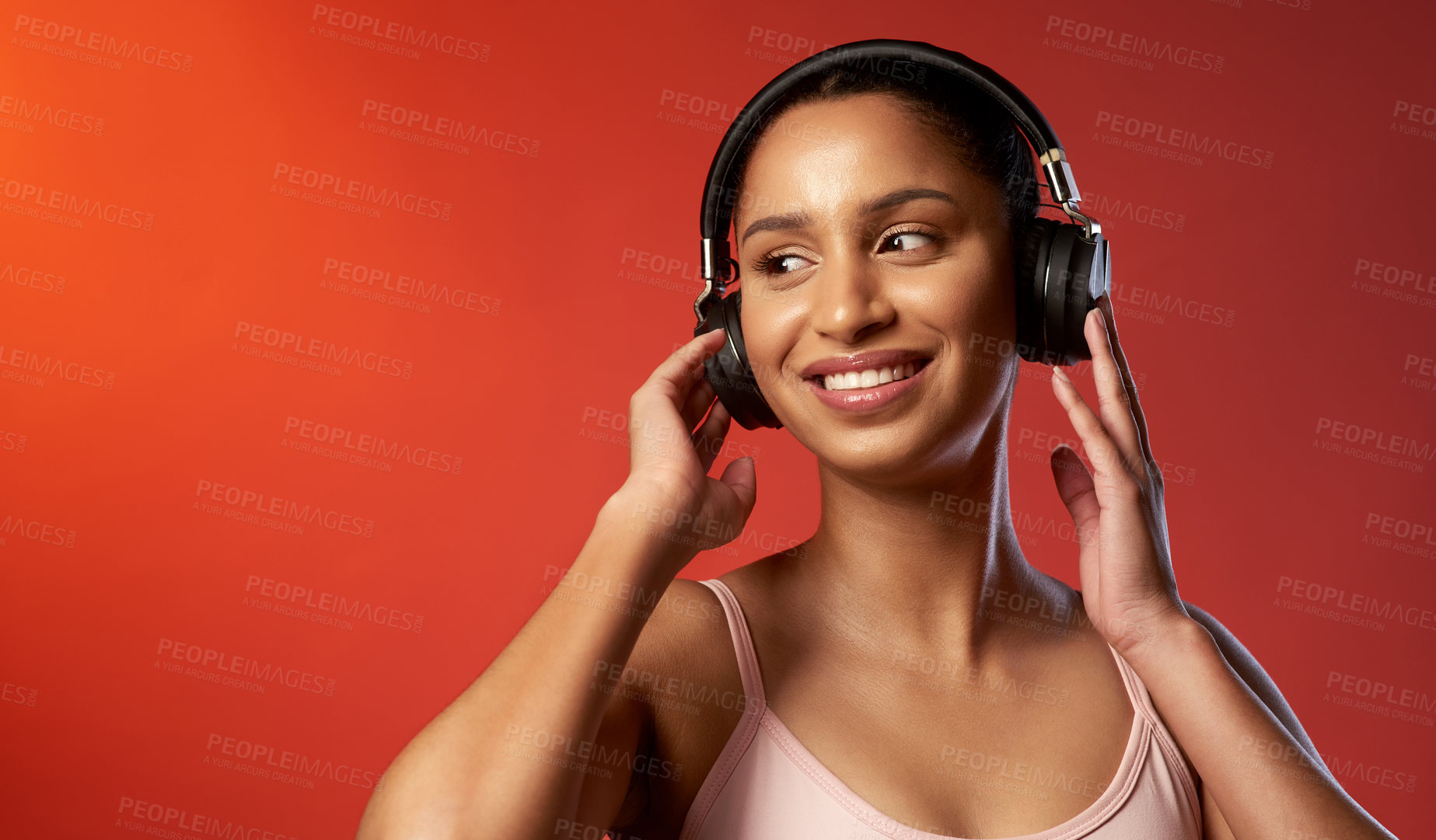 Buy stock photo Studio shot of a sporty young woman listening to music against a red background