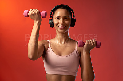 Buy stock photo Studio portrait of a sporty young woman exercising with dumbbells against a red background