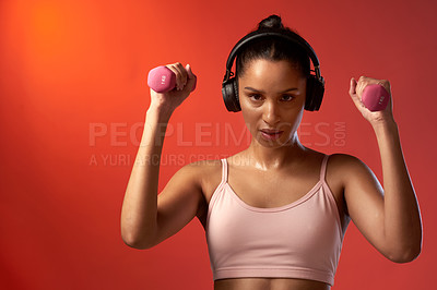 Buy stock photo Studio portrait of a sporty young woman exercising with dumbbells against a red background