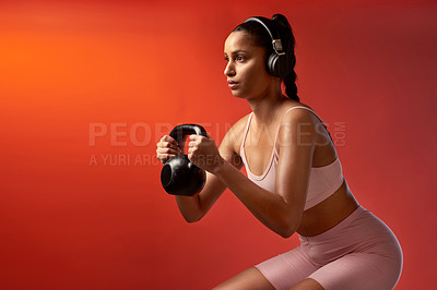 Buy stock photo Studio shot of a sporty young woman doing kettlebell squats against a red background