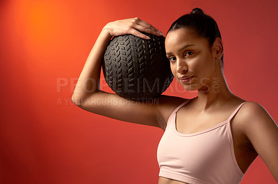 Buy stock photo Studio portrait of a sporty young woman holding an exercise ball against a red background