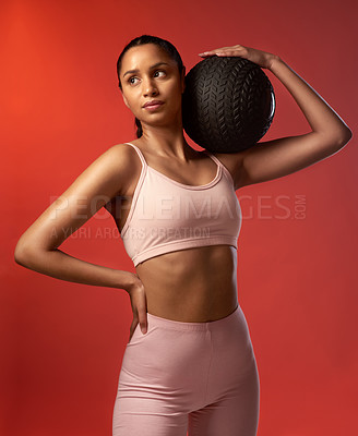 Buy stock photo Studio shot of a sporty young woman holding an exercise ball against a red background