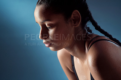 Buy stock photo Studio shot of a sporty young woman catching her breath against a blue background