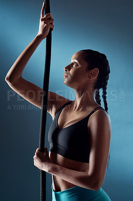 Buy stock photo Studio shot of a sporty young woman getting ready to climb a rope against a blue background