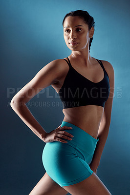 Buy stock photo Studio shot of a sporty young woman posing against a blue background