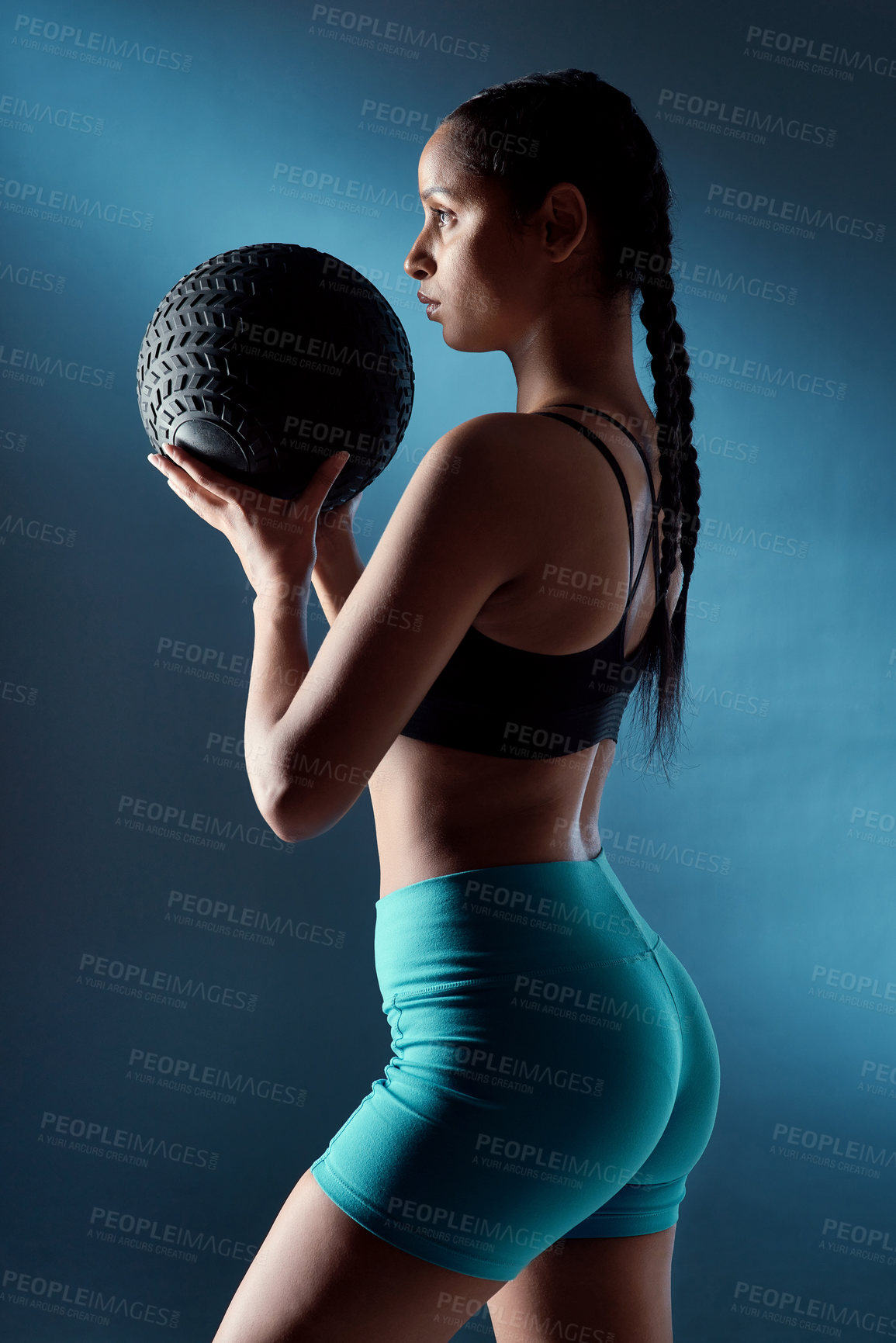 Buy stock photo Studio shot of a sporty young woman holding an exercise ball against a blue background