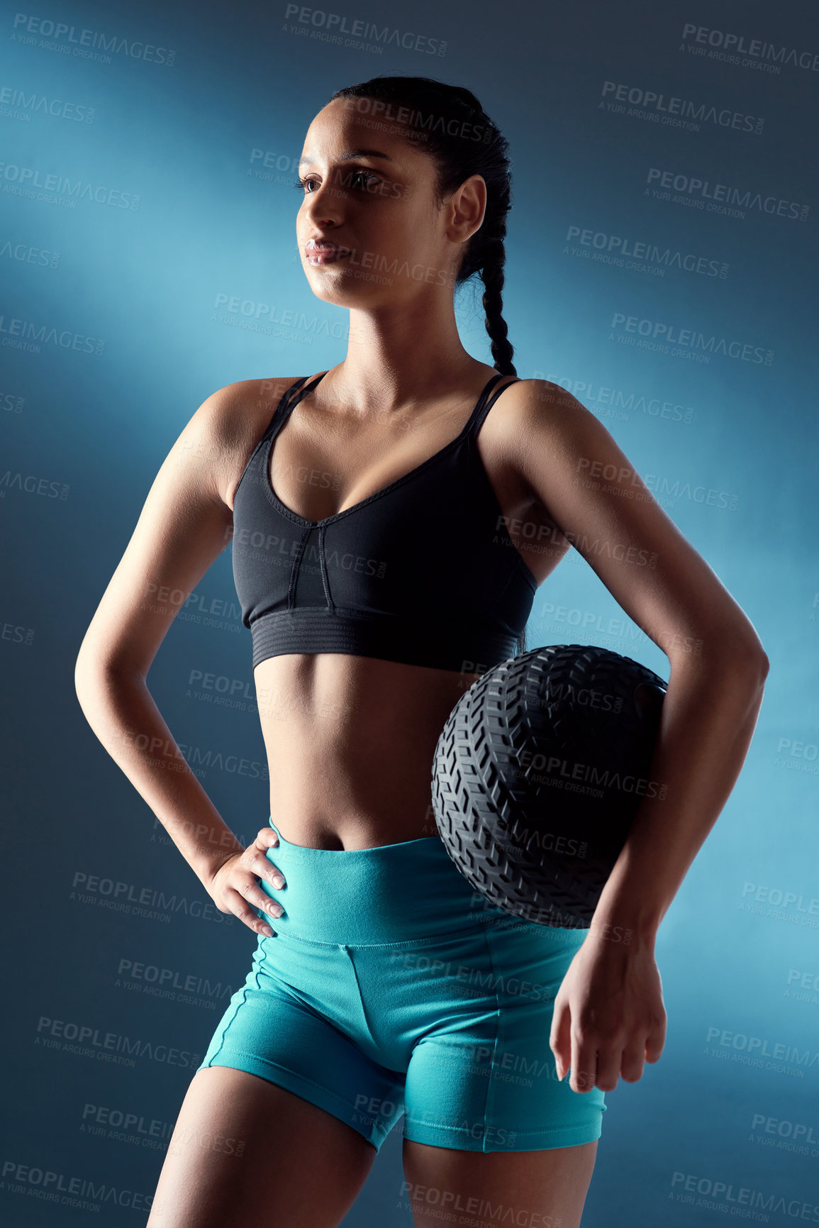 Buy stock photo Studio shot of a sporty young woman holding an exercise ball against a blue background