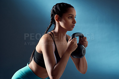Buy stock photo Studio shot of a sporty young woman doing kettlebell squats against a blue background