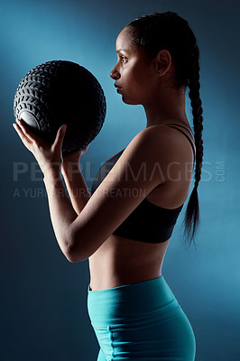 Buy stock photo Studio shot of a sporty young woman holding an exercise ball against a blue background