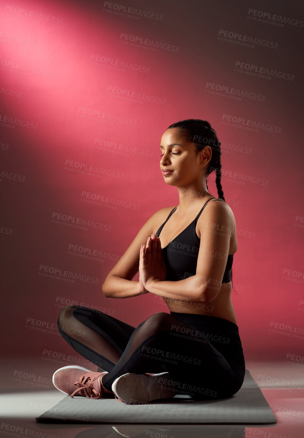 Buy stock photo Studio shot of a sporty young woman meditating against a red background