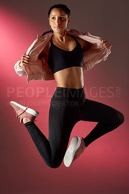 Buy stock photo Studio shot of a sporty young woman jumping against a red background