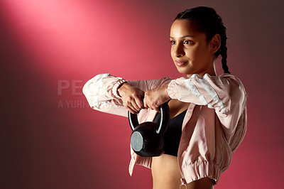 Buy stock photo Studio shot of a sporty young woman exercising with a kettlebell against a red background