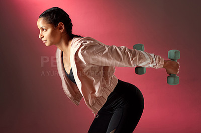 Buy stock photo Studio shot of a sporty young woman exercising with dumbbells against a red background