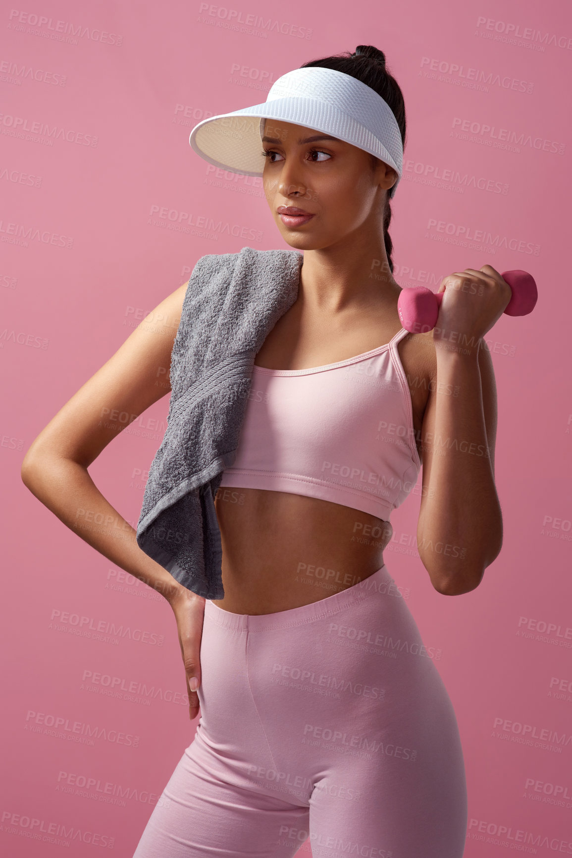 Buy stock photo Cropped shot of an attractive and sporty young woman posing with a towel and a dumbbell in studio against a pink background