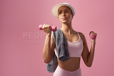 Buy stock photo Cropped shot of an attractive and sporty young woman posing with a towel and dumbbells in studio against a pink background