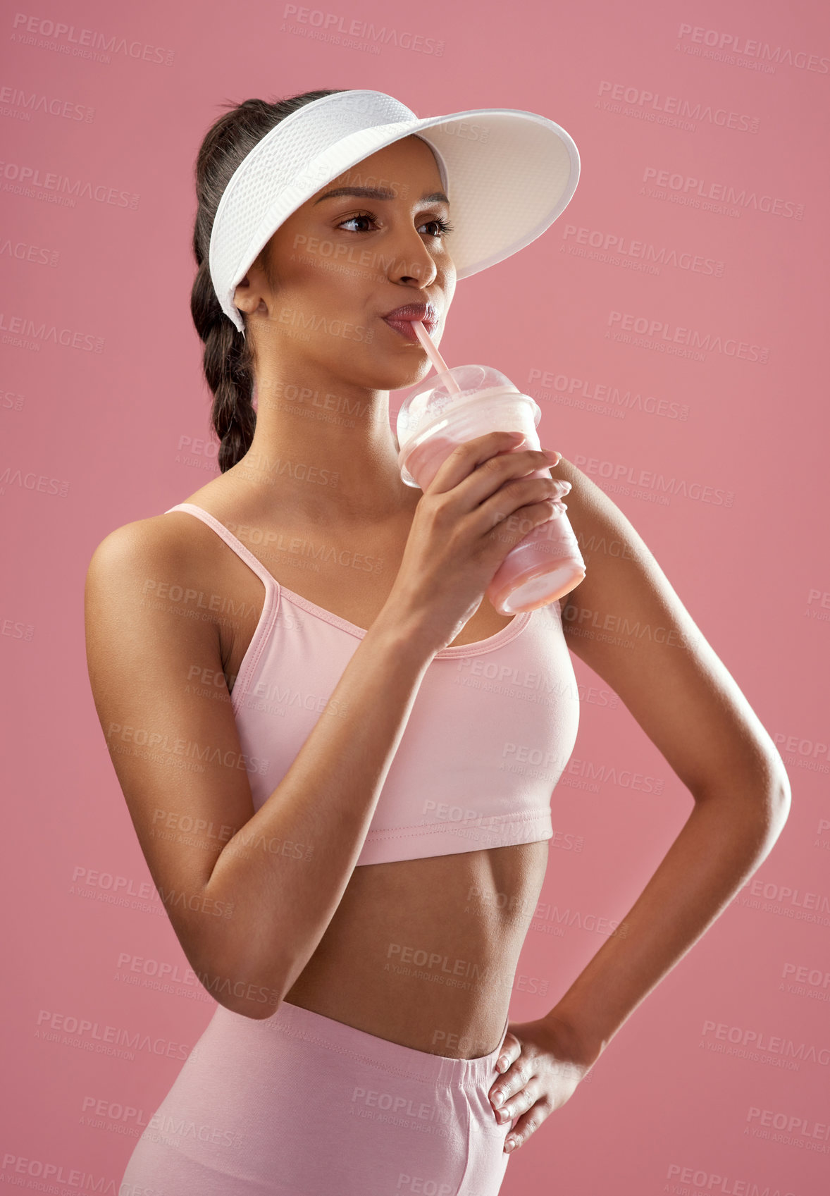 Buy stock photo Cropped shot of an attractive and sporty young woman posing with a smoothie in studio against a pink background