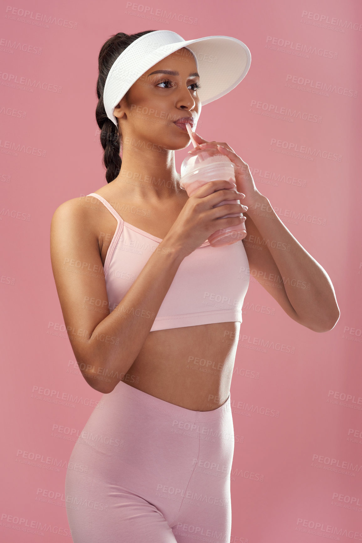 Buy stock photo Cropped shot of an attractive and sporty young woman posing with a smoothie in studio against a pink background