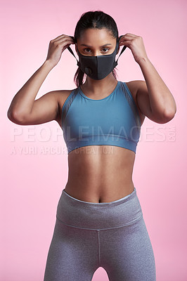 Buy stock photo Cropped portrait of an attractive and sporty young woman wearing a mask while posing in studio against a pink background