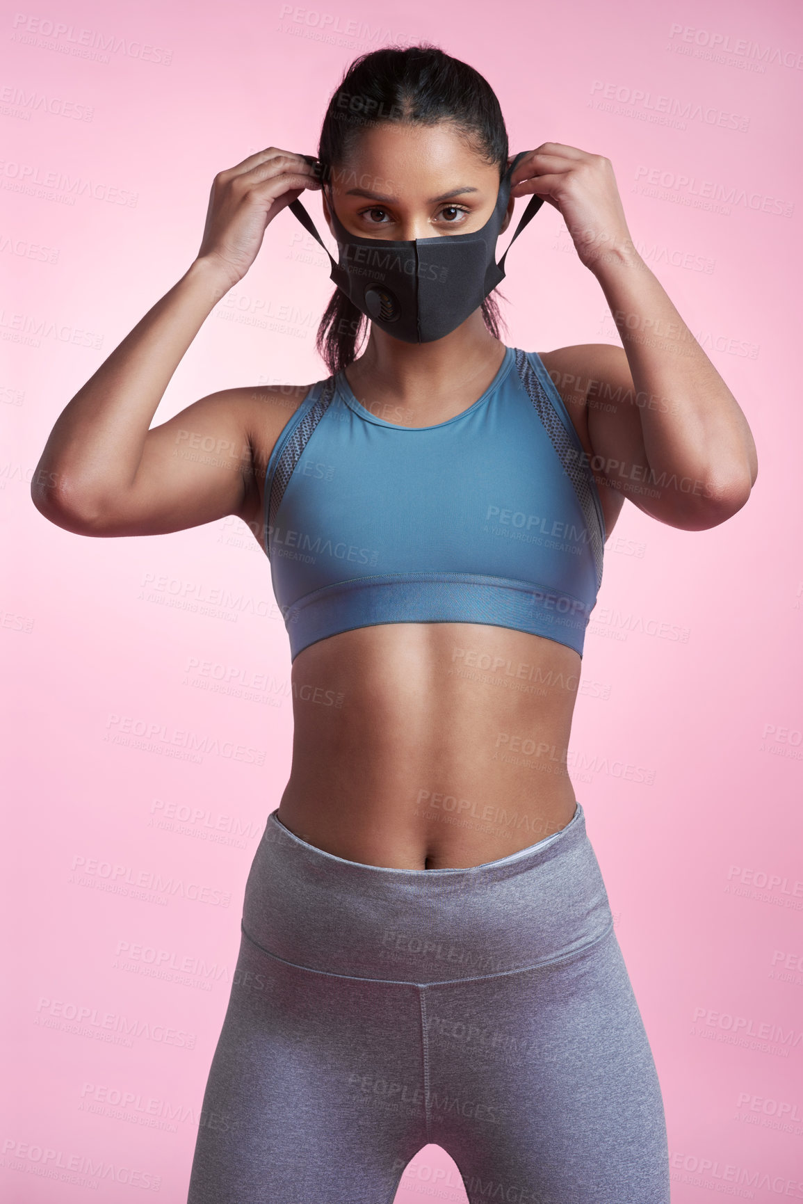 Buy stock photo Cropped portrait of an attractive and sporty young woman wearing a mask while posing in studio against a pink background