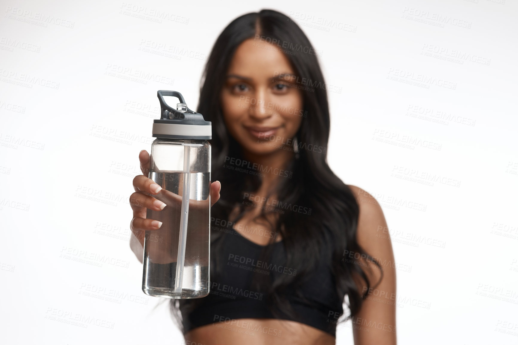 Buy stock photo Studio portrait of a sporty young woman holding a water bottle against a white background