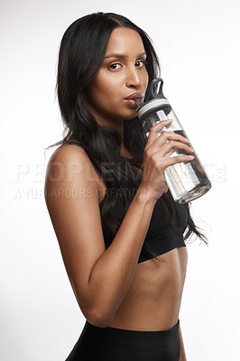 Buy stock photo Studio portrait of a sporty young woman drinking water against a white background