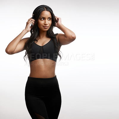 Buy stock photo Studio shot of a sporty young woman listening to music against a white background