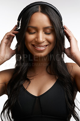 Buy stock photo Studio shot of a sporty young woman listening to music against a white background