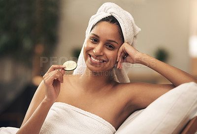 Buy stock photo Shot of a woman holding a slice of cucumber while relaxing at a spa