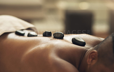 Buy stock photo Cropped shot of a man getting a hot stone massage at a spa