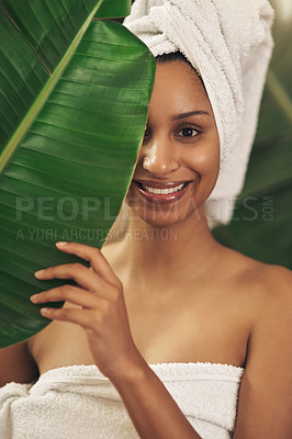 Buy stock photo Shot of a beautiful young woman wearing a towel around her head while posing behind a green leaf