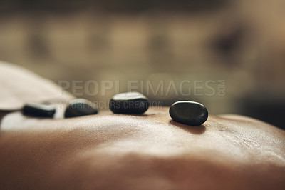 Buy stock photo Cropped shot of a man getting a hot stone massage at a spa